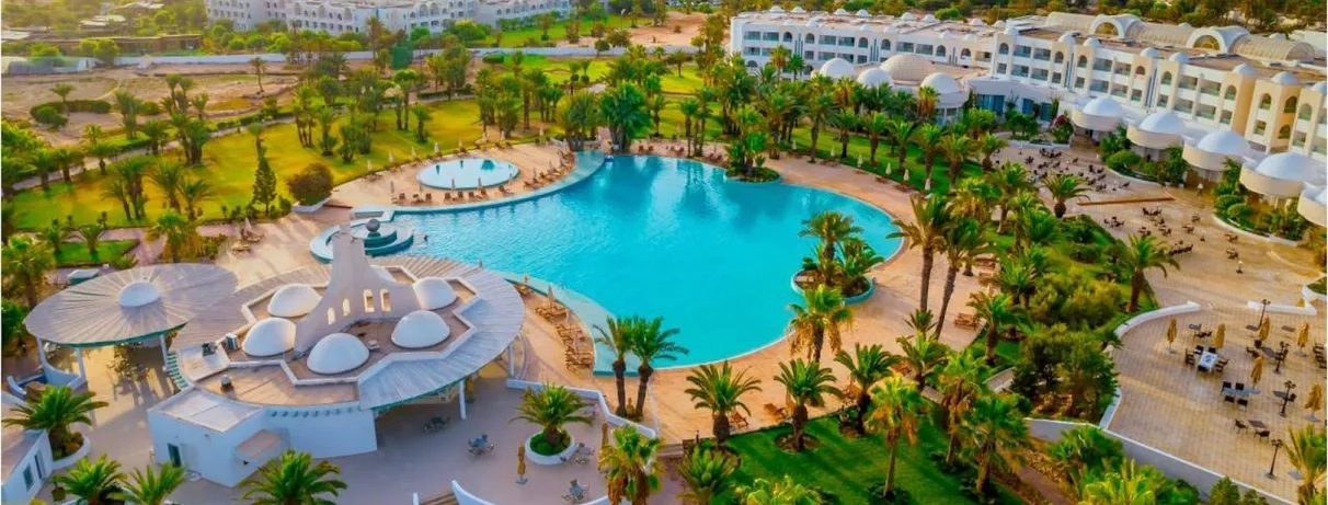 Vue aérienne panoramique du Royal Garden Palace à Djerba, incluant piscine lagon, jardins et architecture tunisienne.
