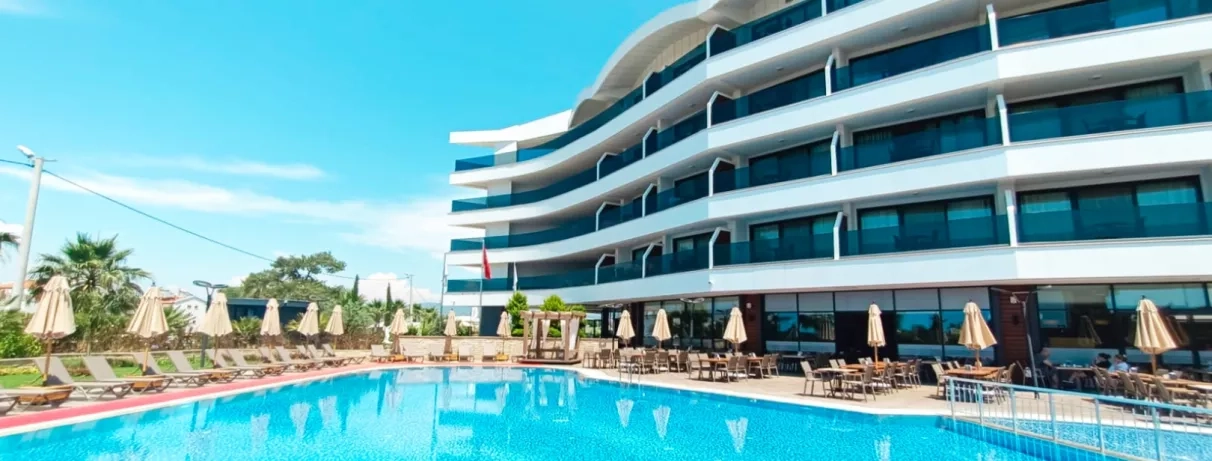 Une vue des balcons filants de l'hôtel bordant une grande piscine sous un ciel dégagé.
