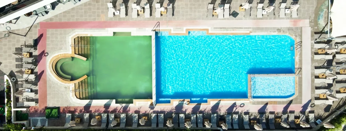 Un plan large montrant l'aménagement paysager des piscines et des espaces extérieurs de l'établissement.
