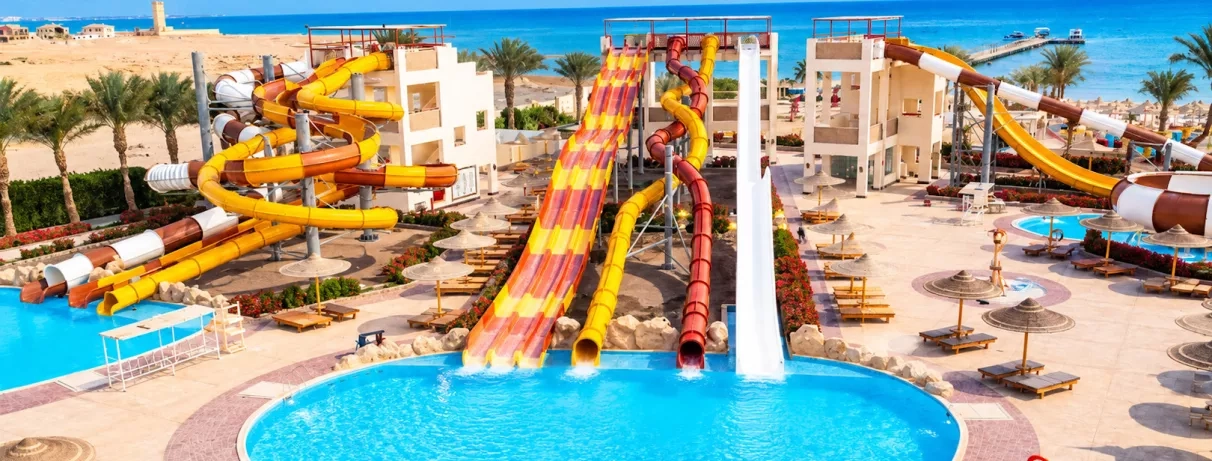 Parc aquatique avec grands toboggans colorés et piscine de l'hôtel El Karma Aqua Beach Resort à Hurghada, Égypte.