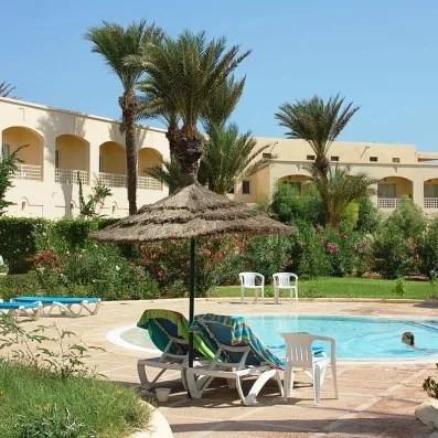 Piscine extérieure relaxante entourée de transats et de palmiers sous le soleil radieux de Djerba.