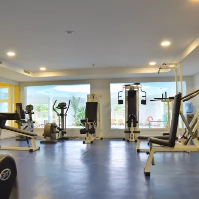 Salle de sport moderne avec équipements de cardio et musculation vue sur piscine au Royal Garden Palace.