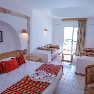 Chambre spacieuse de l'hôtel Al Jazira à Djerba avec décoration tunisienne traditionnelle et balcon ensoleillé.