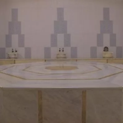 Un hammam traditionnel spacieux en marbre et des fontaines murales.
