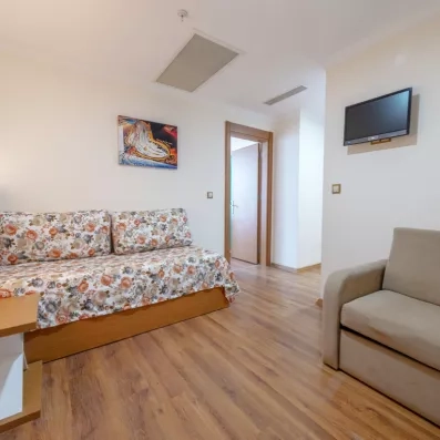 Un coin salon intégré à une suite avec un canapé-lit et un fauteuil beige.