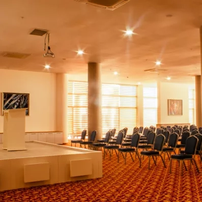 Une vaste salle de conférence lumineuse avec des rangées de chaises.