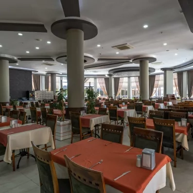 Un grand restaurant, rempli de tables dressées avec des chaises en bois.