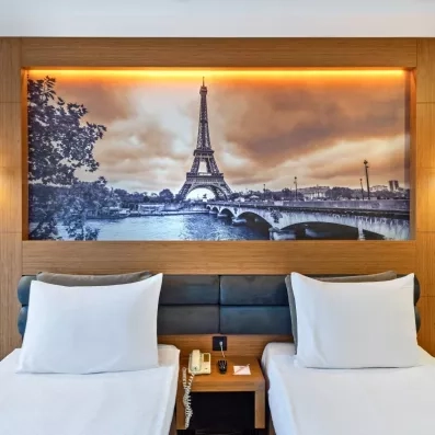 chambre avec deux lits simples et un grand tableau au-dessus du lit