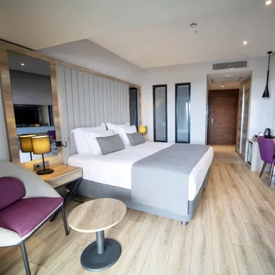 Une chambre double lumineuse, avec un fauteuil et une chaise de bureau.