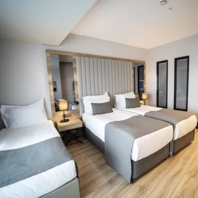 Une chambre spacieuse disposant de trois lits simples alignés sous une tête de lit matelassée élégante.