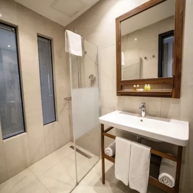 Une salle de bain avec une douche à l'italienne, complétée par de grandes fenêtres.