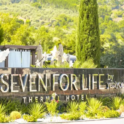 L'enseigne élégante de l'hôtel s'affiche sur un muret noir, entourée de verdure luxuriante.