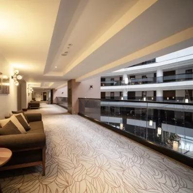 Un couloir moderne et lumineux dispose de canapés confortables bordant un atrium ouvert.