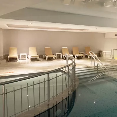 Une piscine thermale intérieure invite à la détente avec ses chaises longues.
