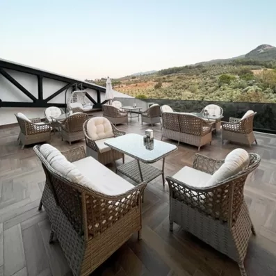 Une terrasse avec du mobilier en rotin offrant une vue panoramique sur les collines.