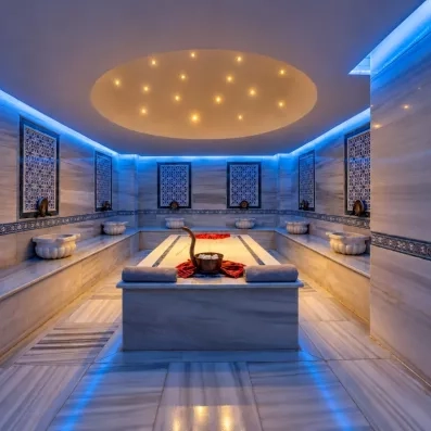 Un bain turc traditionnel luxueux avec des dalles de marbre et un éclairage bleu apaisant.