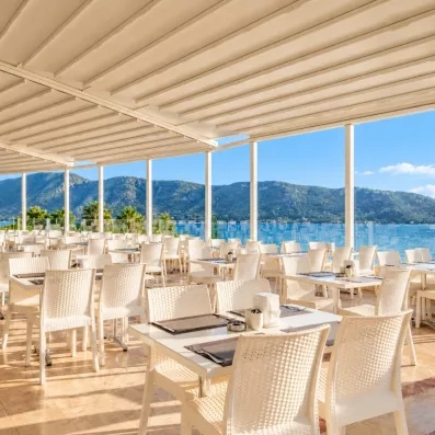 Une terrasse lounge élégante avec des fauteuils en résine blanche offrant une vue imprenable sur la mer.