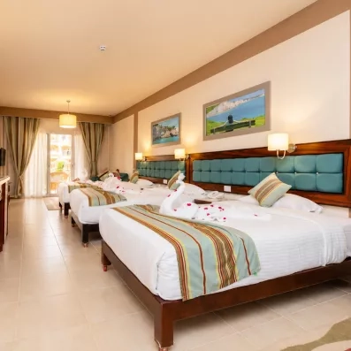 Chambre familiale spacieuse avec plusieurs lits et décoration en serviettes à l'hôtel El Karma Aqua Beach Resort Hurghada Égypte.