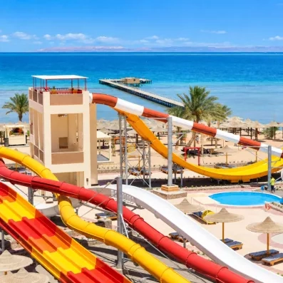 Toboggans colorés du parc aquatique de l'hôtel El Karma Aqua Beach Resort à Hurghada avec vue sur la mer Rouge.